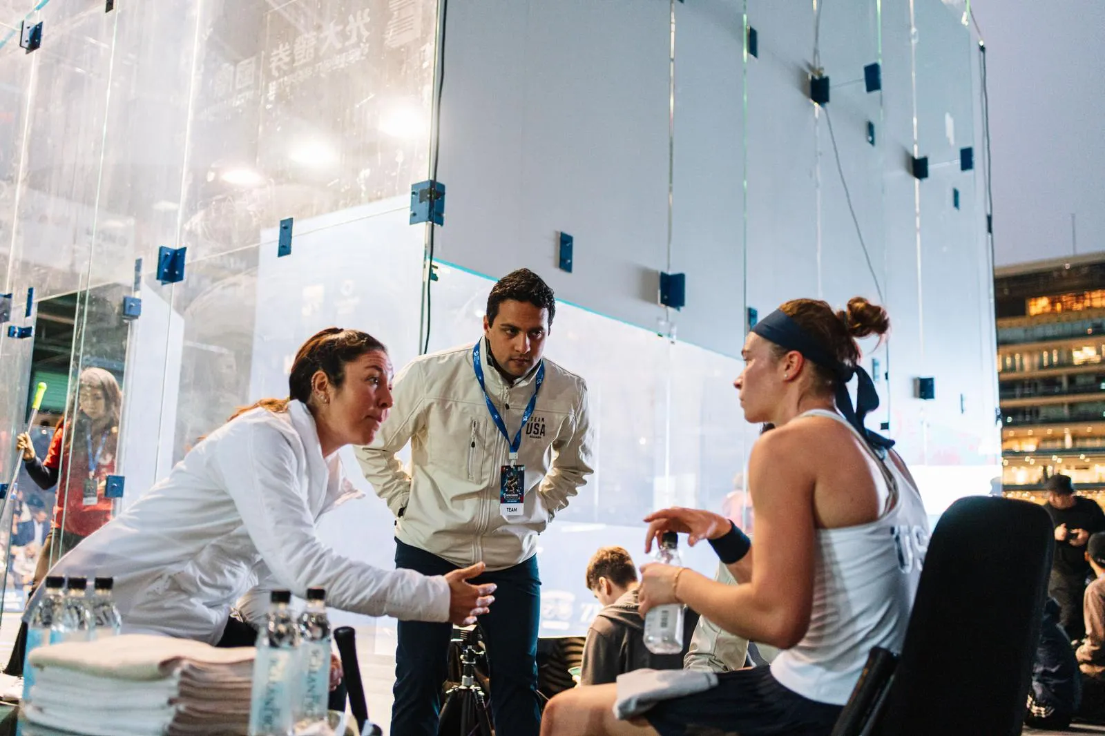 Coaches discussing play with an athlete courtside
